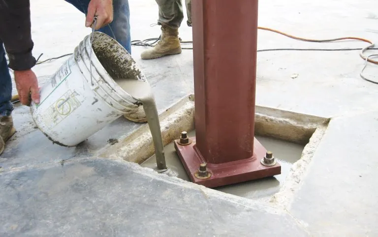 Precision non-shrink grout being poured under structural column baseplate