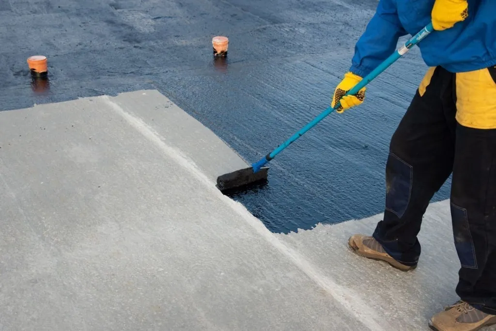 Applicator rolling seamless elastomeric waterproofing membrane onto concrete deck