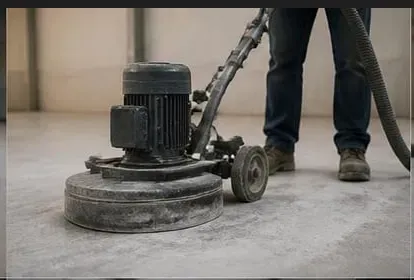 Worker operating planetary diamond grinder on concrete floor