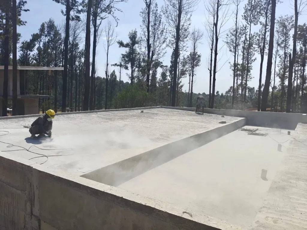 Worker grinding a concrete terrace slab surface before waterproofing