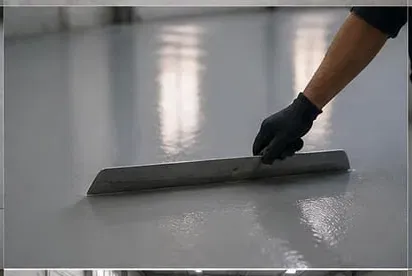 Worker applying epoxy crack and joint filler with a blade on concrete floor