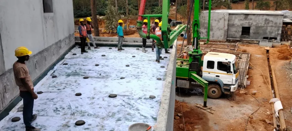 Workers placing protective screed over a waterproofed terrace using a concrete pump