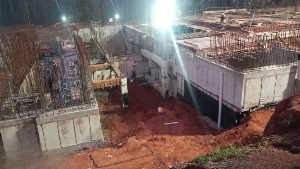 Night-time construction progress showing waterproofed basement wall base